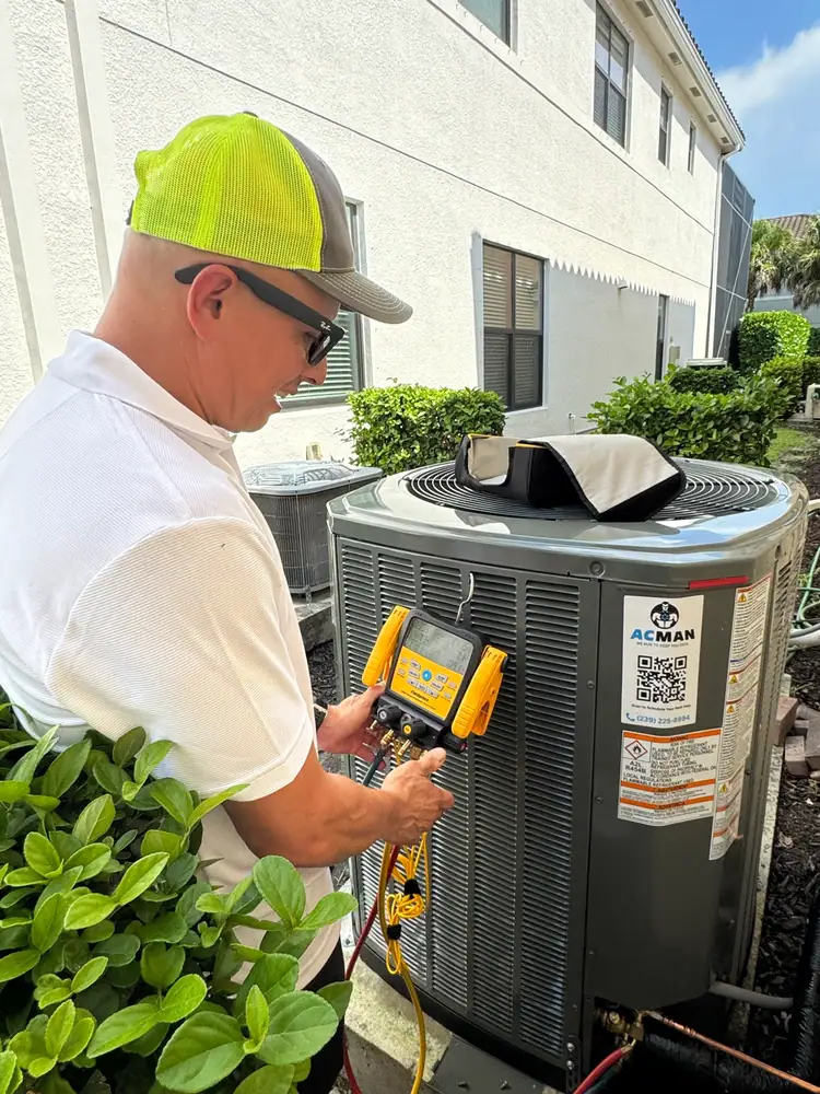 An ACMAN technician checking refrigerant on a condenser with an ACMAN sticker